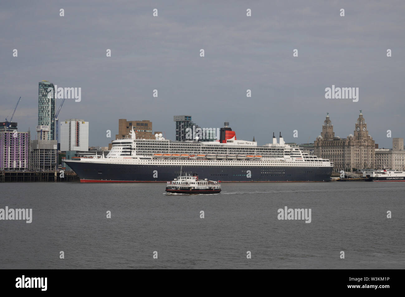 Liverpool, Royaume-Uni. 16 juillet 2019. Le Mersey Ferry Iris Royal passe devant le Queen Mary 2 fait escale à Liverpool. Les 149 000 tonnes de navire le plus grand paquebot jamais construit est sur la vue aujourd'hui tout en amarré au terminal de croisière de la ville. 300 passagers vont la rejoindre dans le cadre d'un voyage transatlantique de New York via Reykjavik et Halifax, en Nouvelle-Écosse. Credit : Ken Biggs/Alamy Live News Banque D'Images