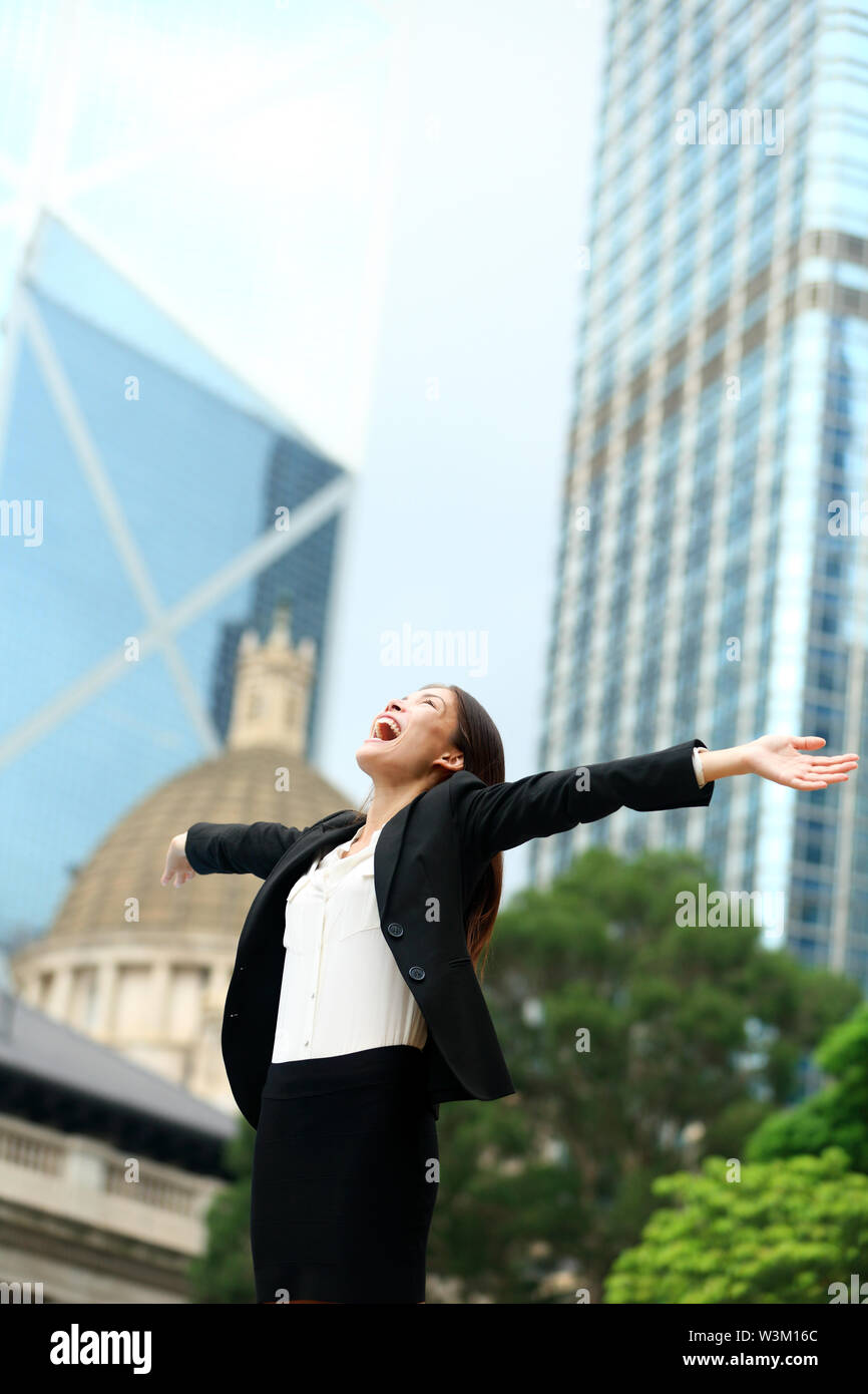 La réussite de l'entreprise avec succès femme à Hong Kong pour célébrer les réalisations d'affaires avec les bras écartés gagner. Young mixed race asiatique chinois / Caucasian female professional in Hong Kong central. Banque D'Images
