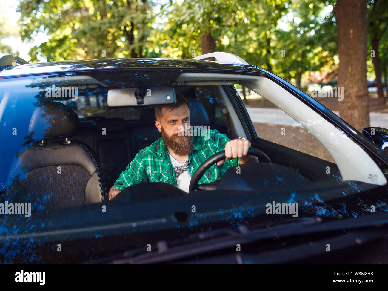 Homme barbu dans la voiture. Jeune homme au volant de sa voiture. Banque D'Images