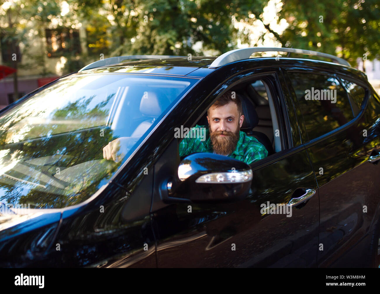 Homme barbu dans la voiture. Jeune homme au volant de sa voiture. Banque D'Images