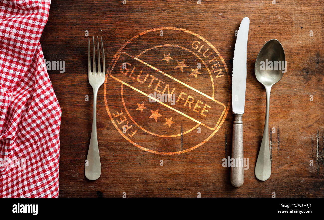 Certifié sans Gluten, de la saine alimentation menu concept. Gluten-free stamp et couverts mis sur table en bois rustique, vue du dessus. Banque D'Images