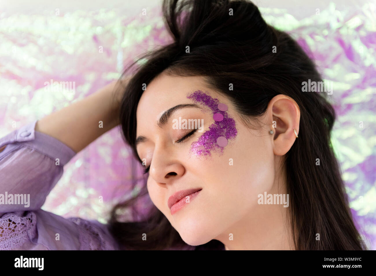 Woman with purple glitter on cheek Banque D'Images