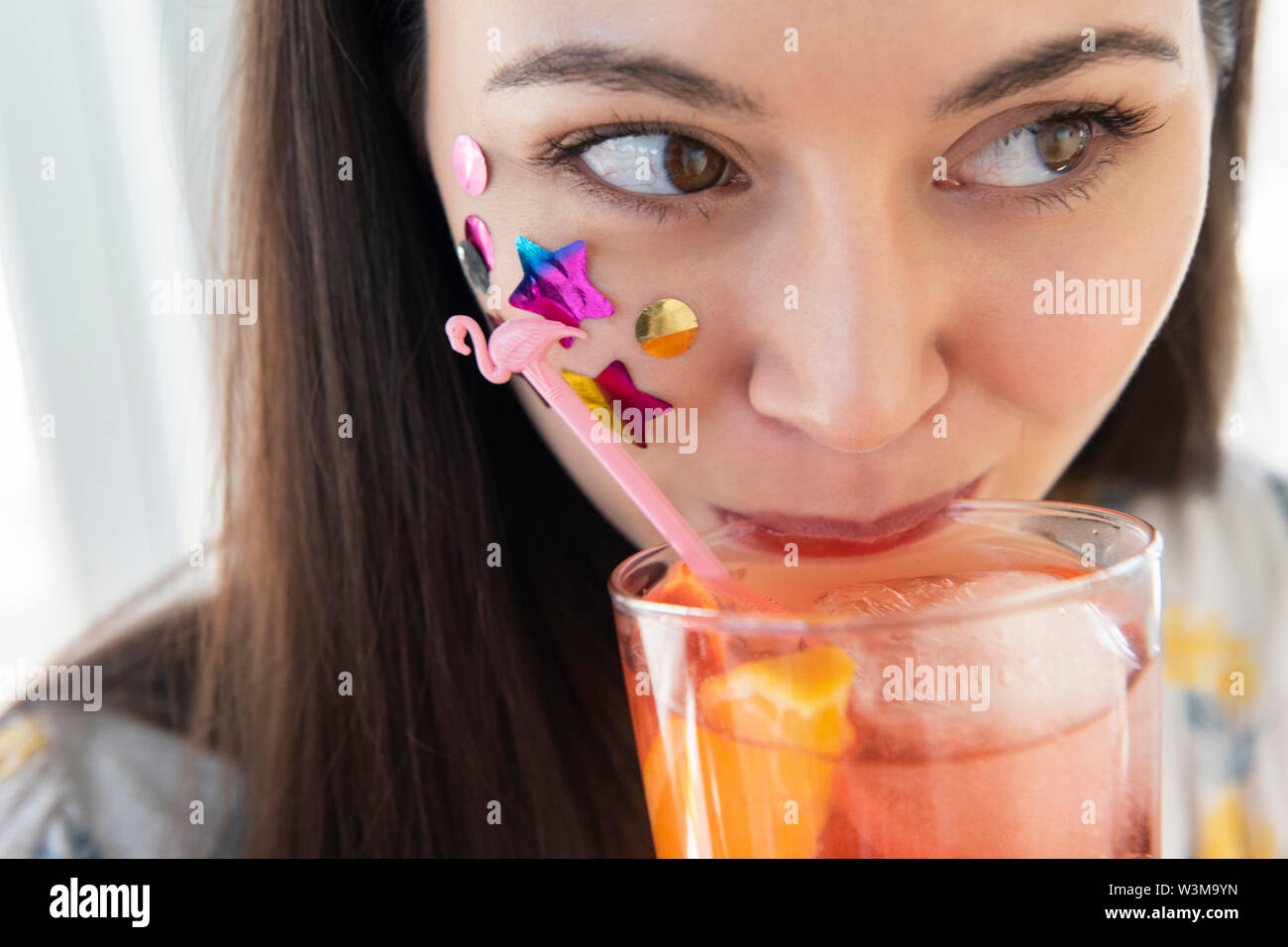 Femme de confettis sur joue drinking cocktail Banque D'Images