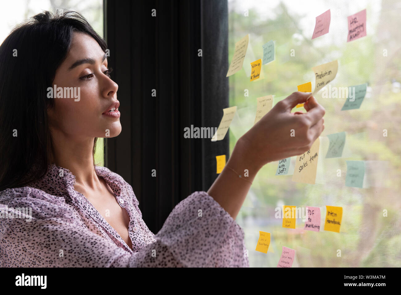 Businesswoman with adhesive notes sur la fenêtre Banque D'Images