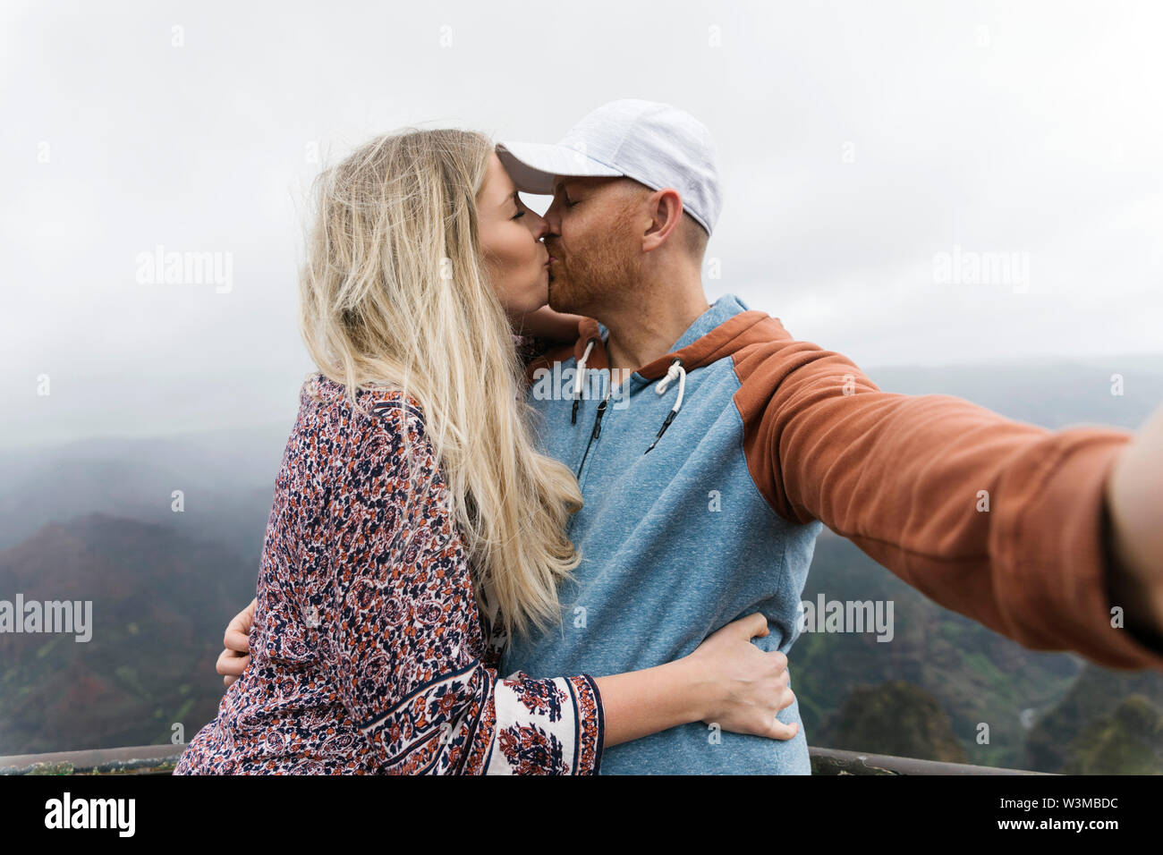 Couple en tenant tout en embrassant selfies Banque D'Images