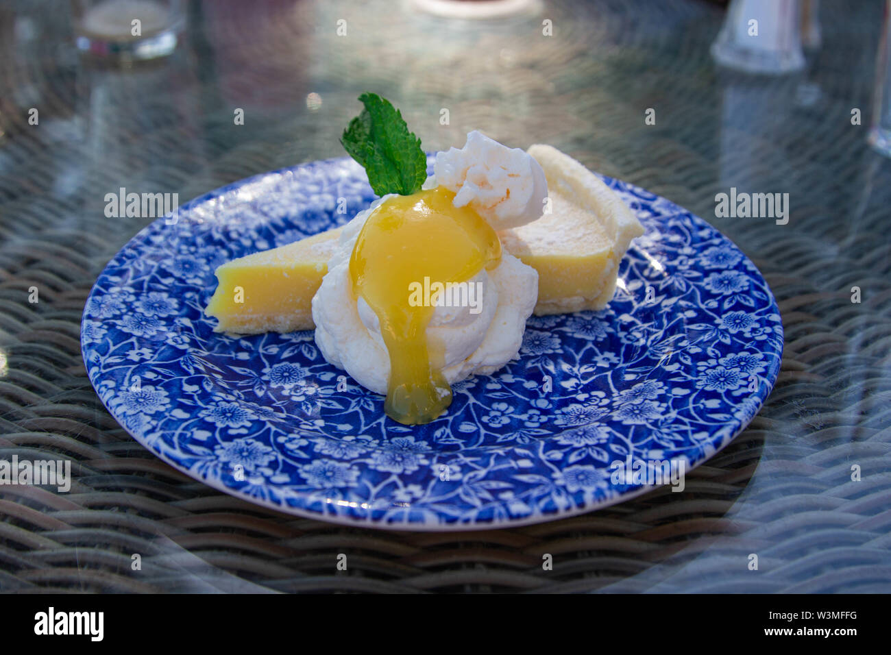 Tarte au citron sans gluten avec crème de mascarpone, le merengue et le lait caillé de citron, garni de menthe fraîche, servi sur un classique bleu chine plaque. Banque D'Images