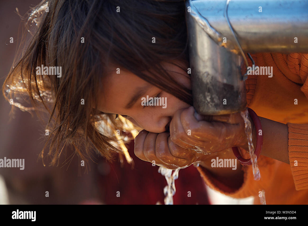 Un enfant boit l'eau d'une pompe à main à Maslakh camp pour personnes déplacées, à la périphérie d'Herat. Il n'est plus un camp officiel, mais encore beaucoup de gens de différentes provinces reculées continuent à venir de se mettre à l'abri de difficultés dans les zones rurales. L'Afghanistan. 20 juin 2007. Banque D'Images