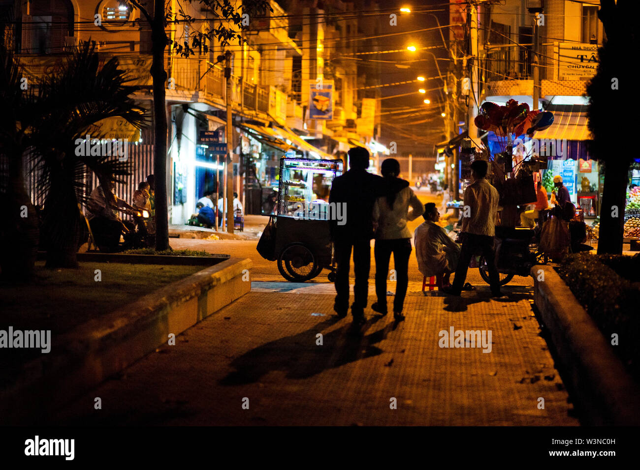 Un jeune couple emprunte la rue la nuit à Ho Chi Minh City Vietnam en Asie du Sud ; Banque D'Images