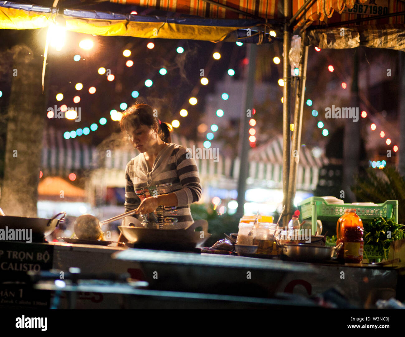 Femme Asiatique prépare la nourriture la nuit dans un restaurant extérieur à Ho Chi Minh Ville, Vietnam du Sud ; Banque D'Images