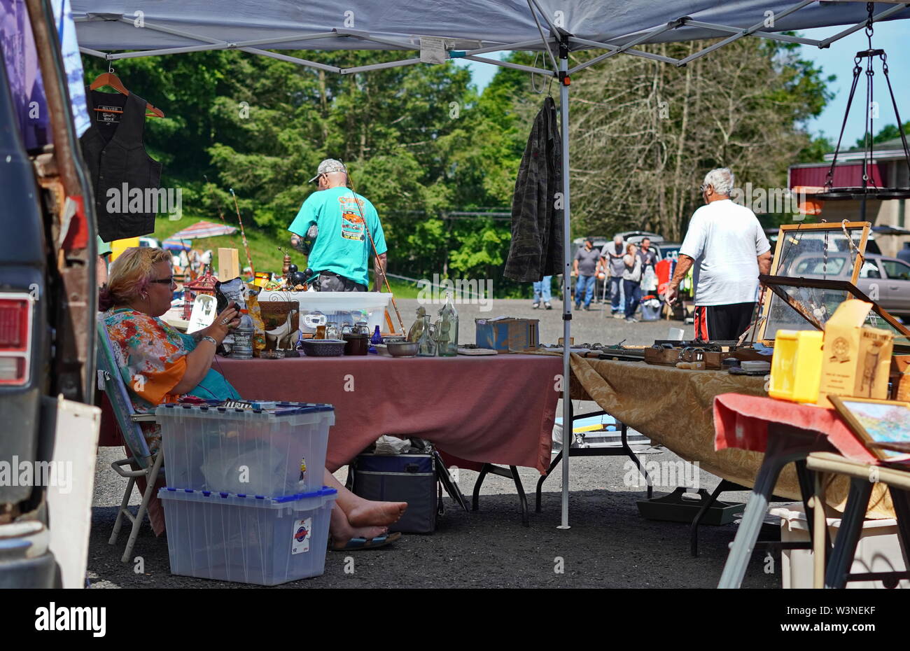 Durham, CT / USA - 24 juin 2019 : vendeur dans un marché aux puces se détend et observe ses marchandises sous l'ombre Banque D'Images