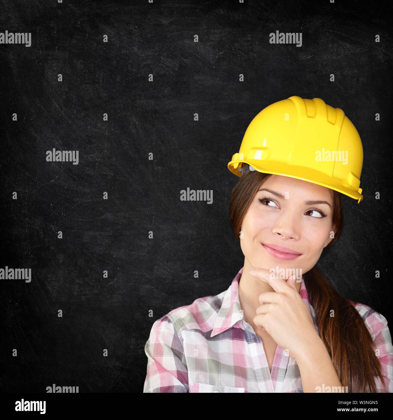 Femme architecte, ingénieur, expert ou un travailleur de la construction portant un casque de protection à la pensée réfléchie sur le côté sur tableau noir tableau de la texture pour copier l'espace. Banque D'Images