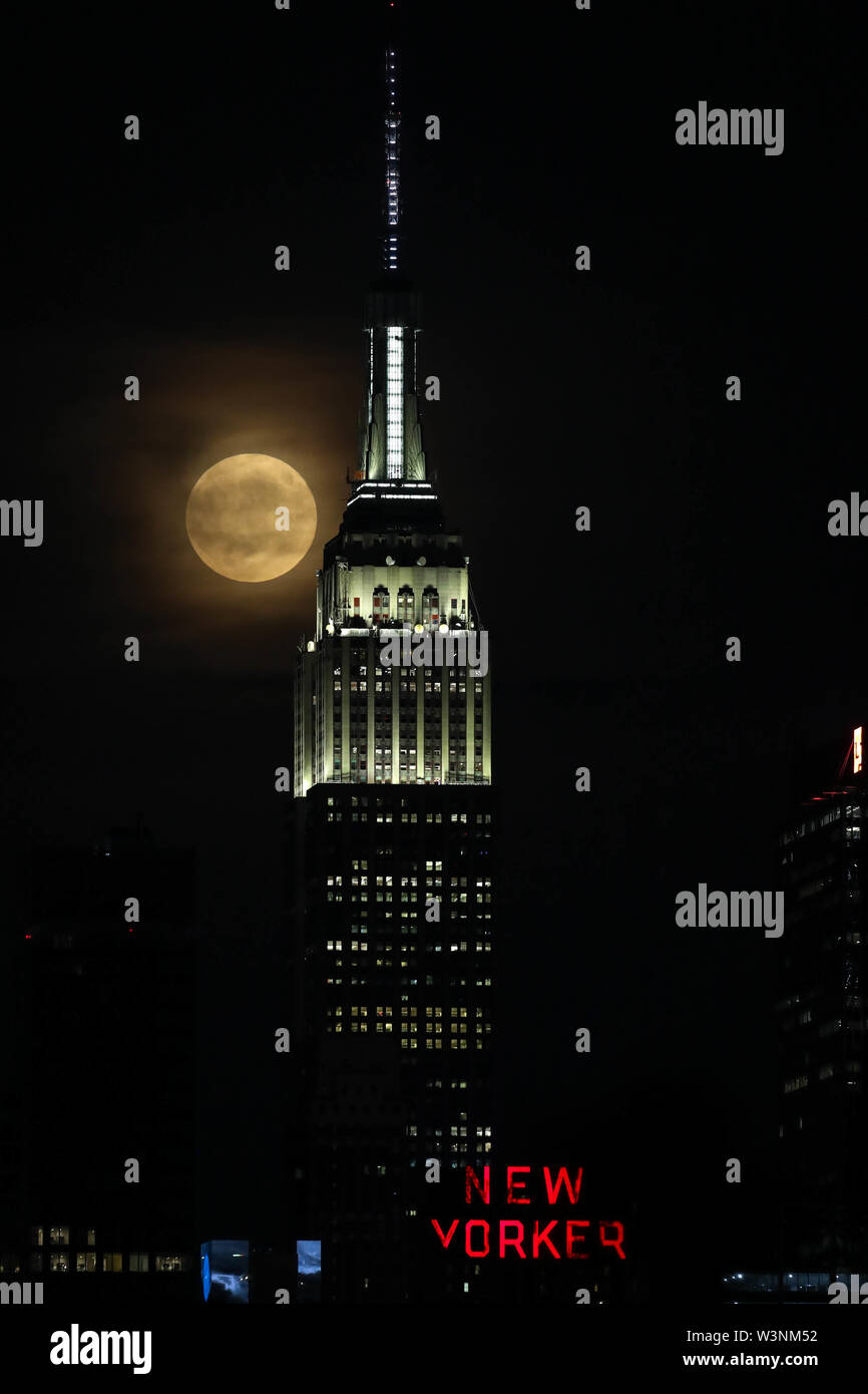 Hoboken, New Jersey, USA. 16 juillet, 2019. Pleine lune est vu près de Empire State Building à New York, de la ville de Hoboken, dans le New Jersey la nuit mardi, 16. Aujourd'hui célèbre 50 ans que Neil Amstrong, le premier homme qui a marché sur la lune. Crédit : William Volcov/ZUMA/Alamy Fil Live News Banque D'Images