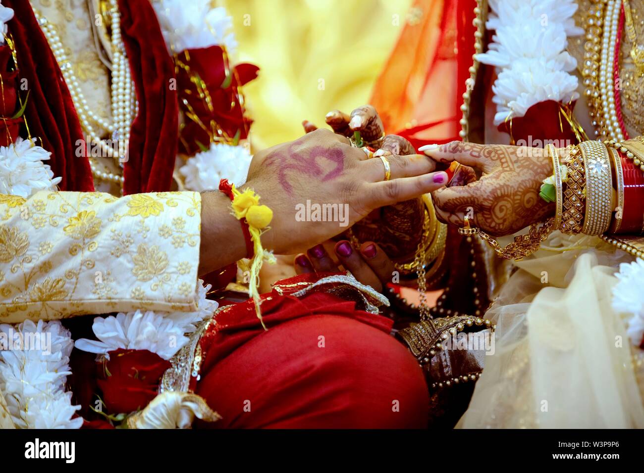 Mariée avec Bijoux de mariée et décoration au henné sur sa main se fixe à l'anneau du doigt de mariés cérémonie religieuse traditionnelle à un mariage hindou Banque D'Images