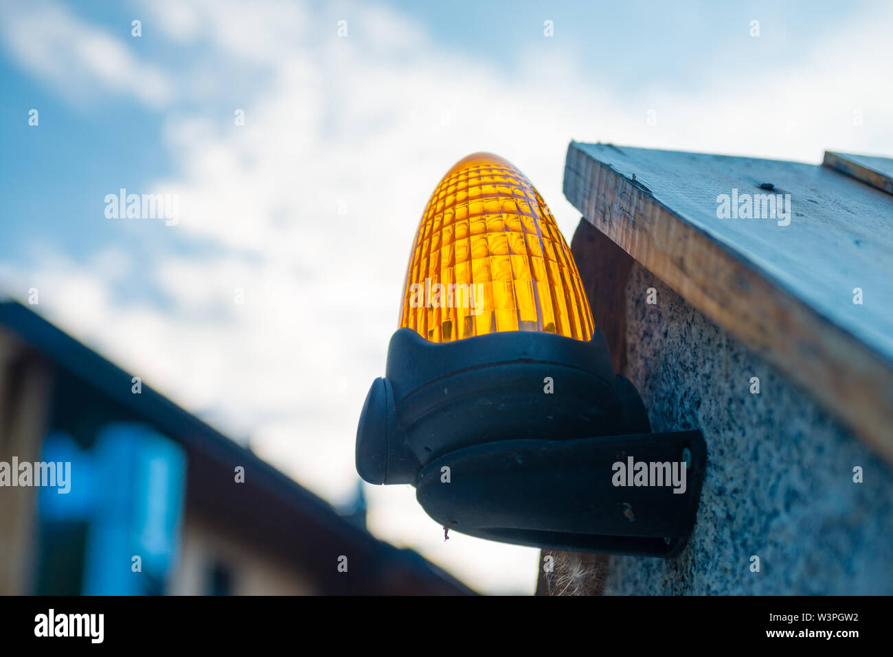 Signal orange lumière à la porte d'entrée automatique à la propriété - contre fond nuageux Banque D'Images