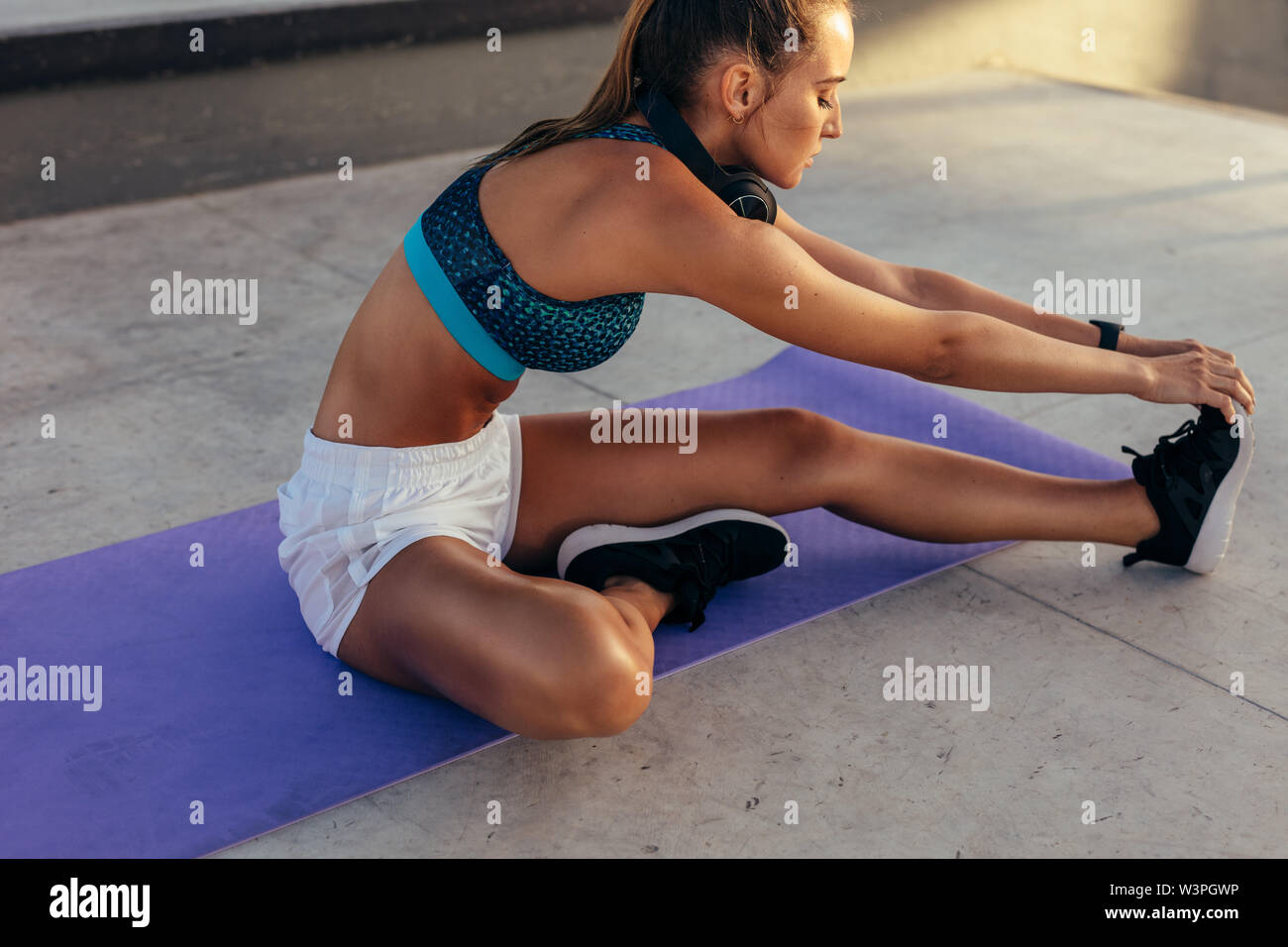 Jeune femme fitness sportswear en étirant la jambe à l'extérieur. Caucasian female relaxing ses muscles des jambes. Banque D'Images