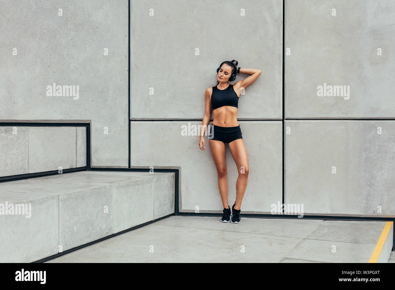 Femme se reposant après l'entraînement. Toute la longueur de sporty young woman relaxing après exécution de l'exercice. Banque D'Images