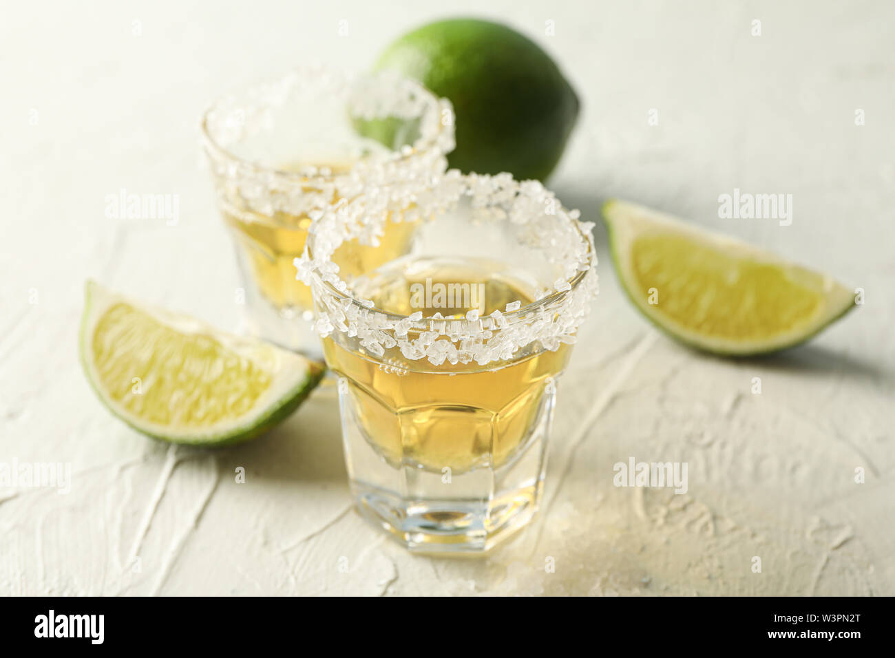 Tequila shots avec sel et citron tranches sur fond blanc Banque D'Images