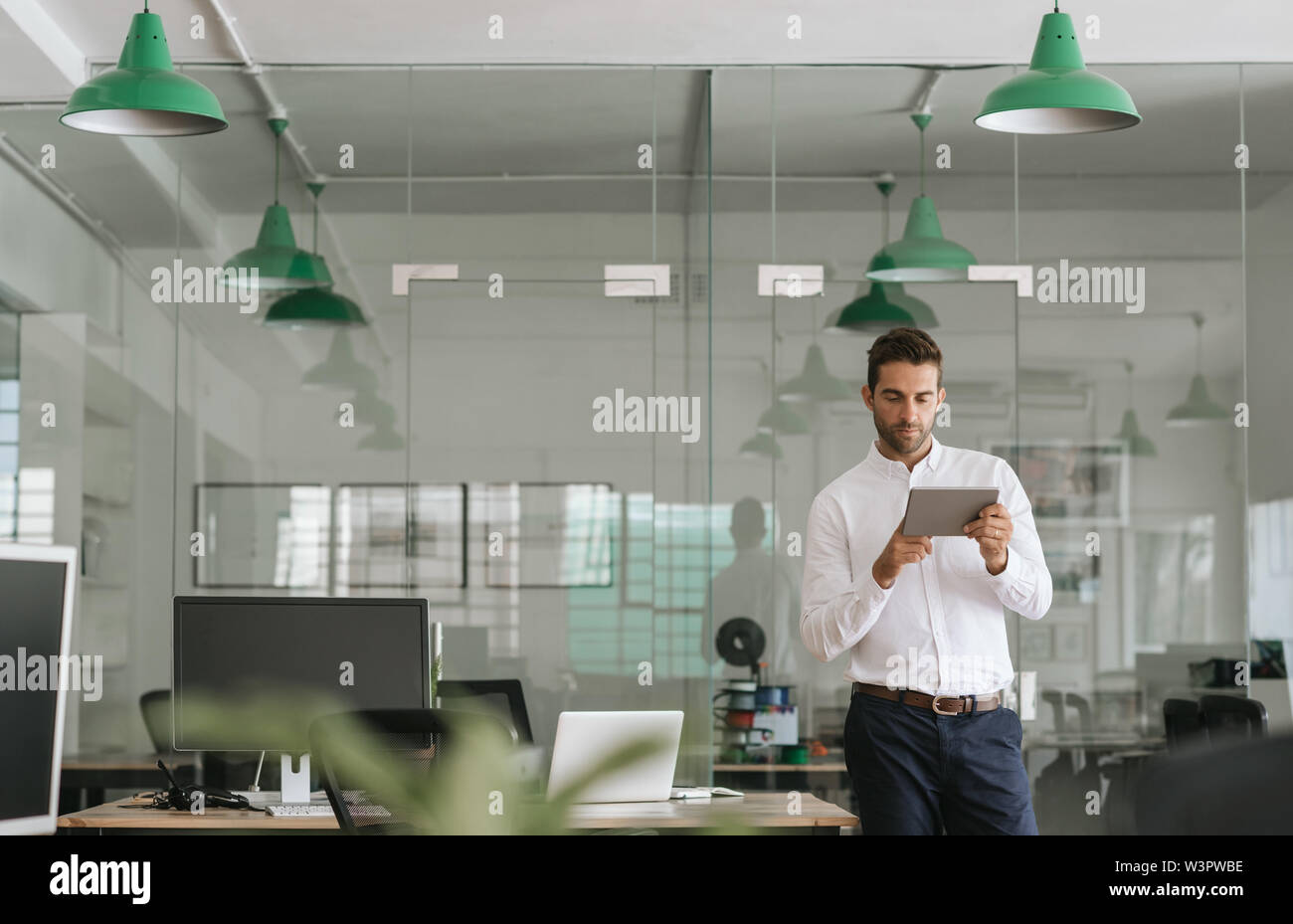Jeune homme d'affaires axée sur une tablette de travail dans un bureau Banque D'Images