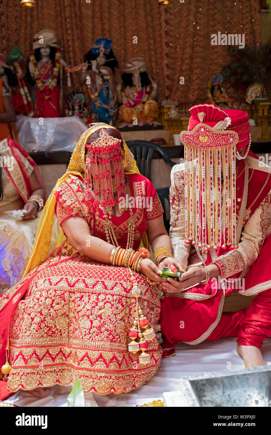 Au cours d'une cérémonie de mariage traditionnelle hindoue, la jeune mariée et se toilettent tenir une fleur sur une feuille. À un service dans le Queens, New York City, Banque D'Images