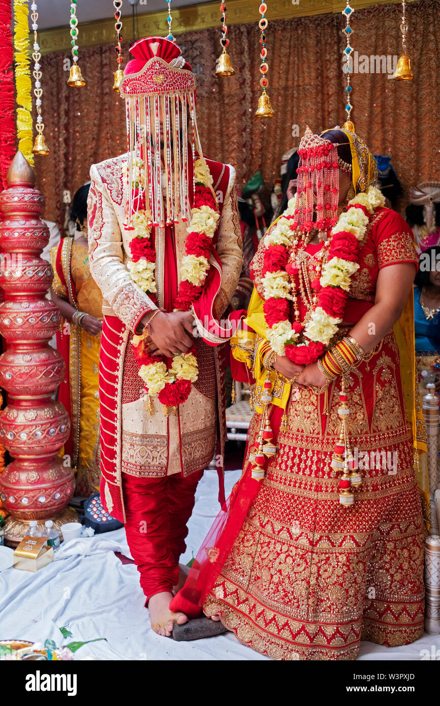 Un hindou bride & groom en vêtements traditionnels se tiennent sur un rocher dans le cadre de leur cérémonie de mariage. Dans le Queens, New York. Banque D'Images