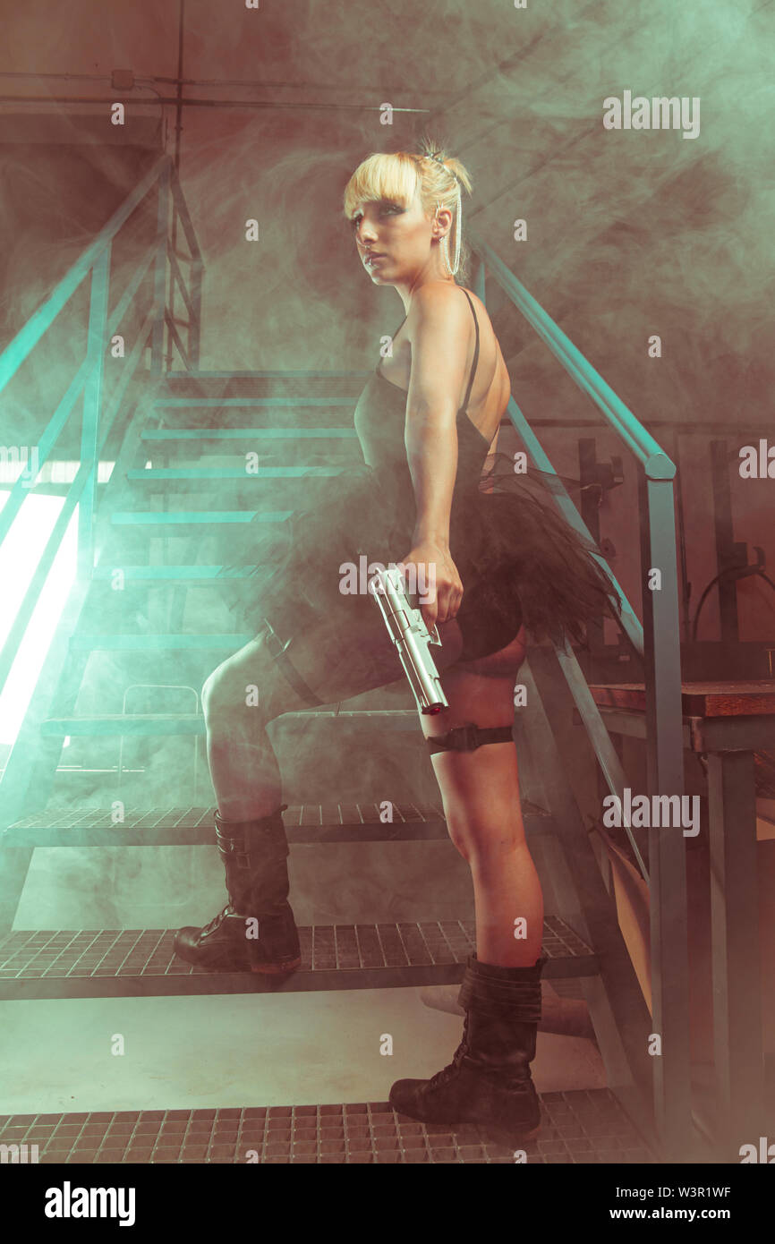 Fille blonde avec des pistolets dans une usine abandonnée. cosplayeuse, d'action et femme dangereuse Banque D'Images