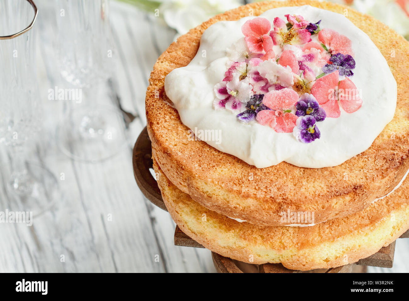 Gâteau éponge Victoria avec crème fouettée et fleurs sucrées sur une table rustique en bois blanc. Capture d'image ci-dessus. Banque D'Images