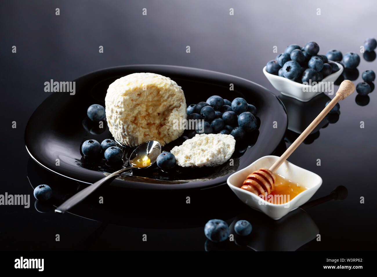 Le fromage blanc avec du miel et de bleuet sur un fond noir. Banque D'Images