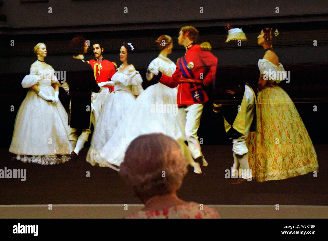 La reine Elizabeth II regarde une technique d'illusion victorienne connue sous le nom de Pepper's Ghost of a Waltz dansé au Crimean ball de 1856, dans la salle de bal de Buckingham Palace, Dans le cadre de l'exposition marquant le 200e anniversaire de la naissance de la reine Victoria pour l'ouverture estivale de Buckingham Palace, Londres. Banque D'Images