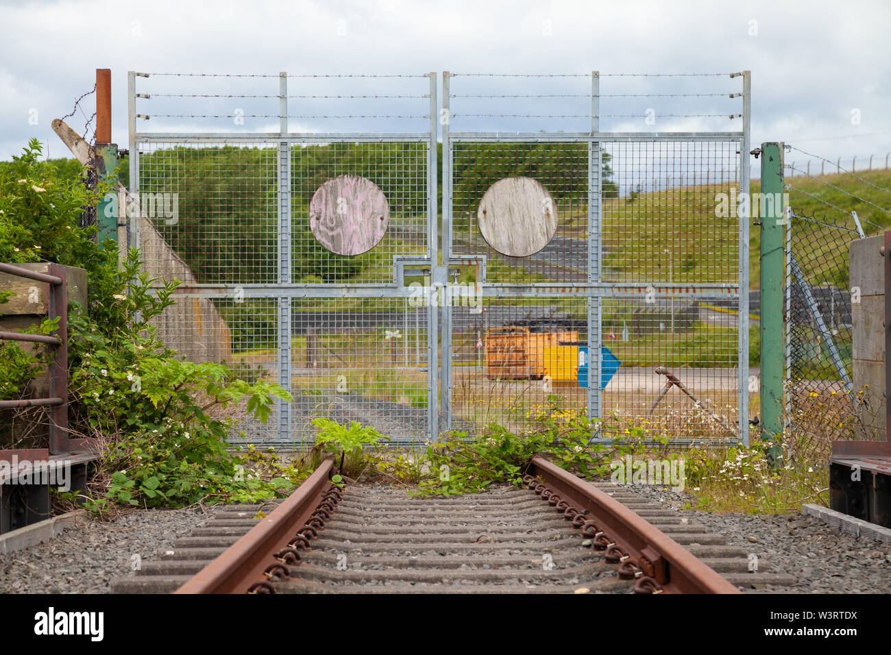 Des grilles verrouillées et les voies ferroviaires avec l'entrée du site. Banque D'Images