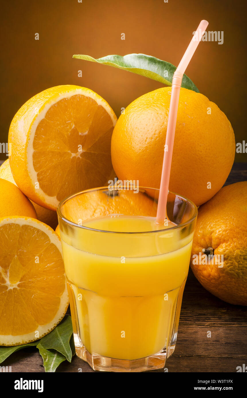 Blonde les oranges et jus d'orange dans un verre avec paille pour siroter Banque D'Images