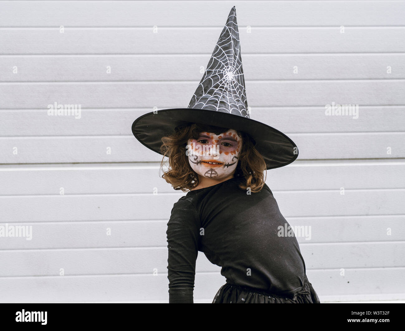Fille vêtue comme une sorcière avec un visage peint looking at camera Banque D'Images