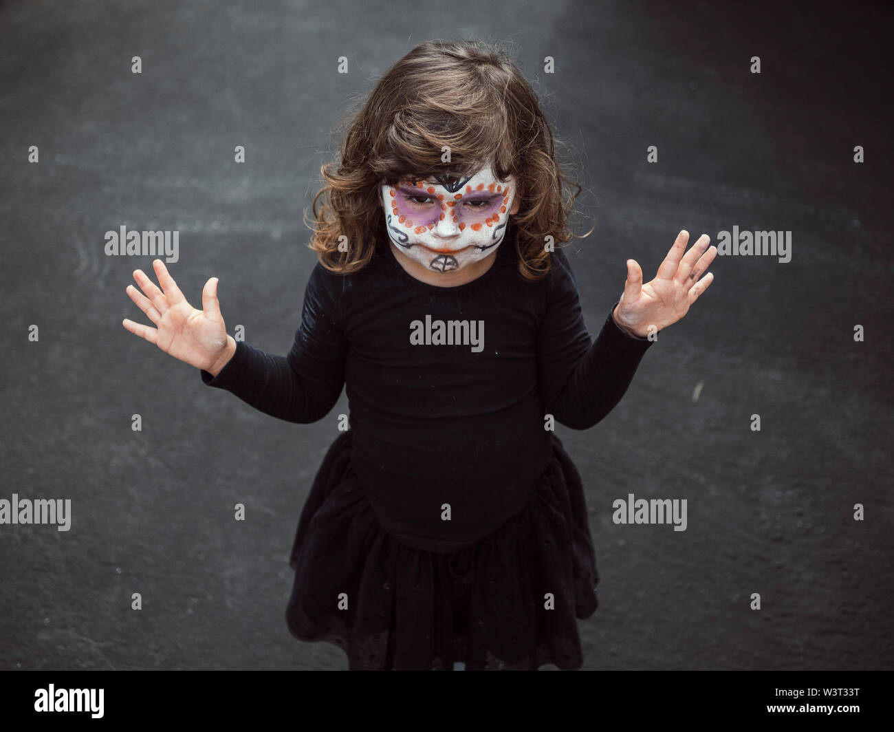 Petite fille au visage peint et déguisée pour halloween avec mains u Banque D'Images