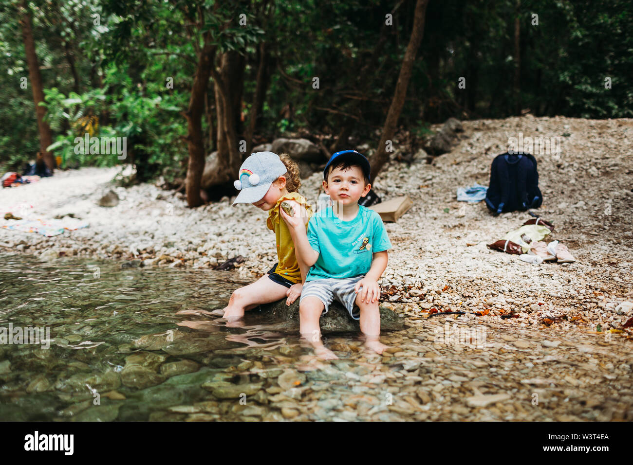 Jeune garçon et fille assise sur un rocher dans l'eau près de Barton Springs Banque D'Images