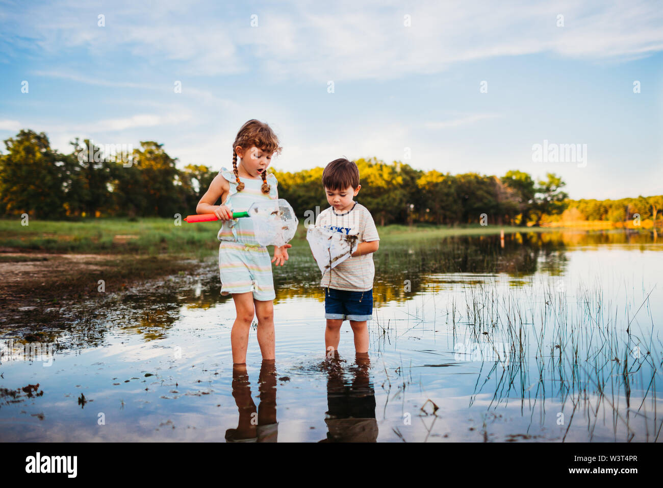 Jeune fille et un garçon à la recherche de poisson dans leurs filets de pêche sur le lac Banque D'Images