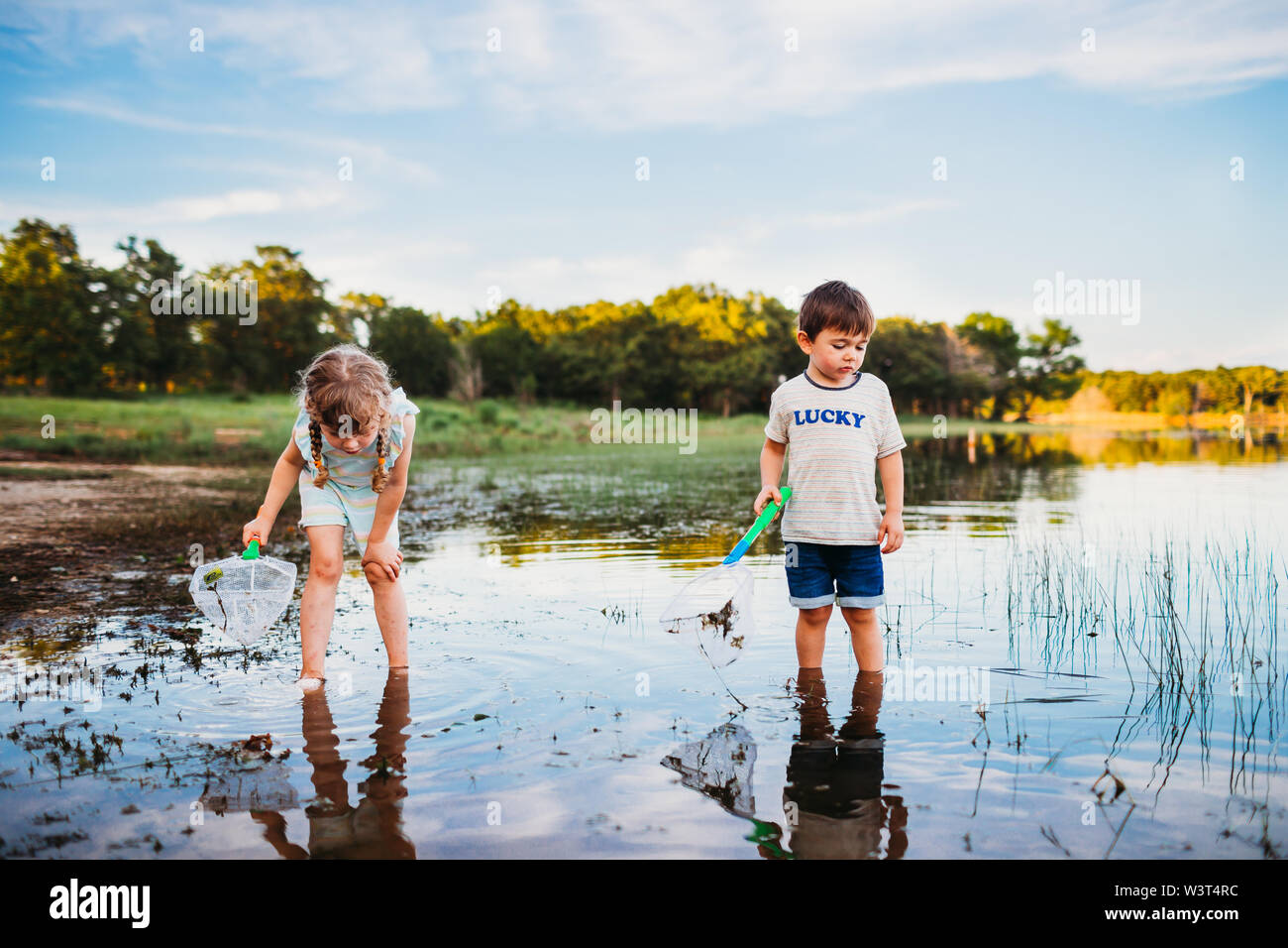 Jeune fille et un garçon à la recherche dans le lac de pêche avec filet de pêche Banque D'Images