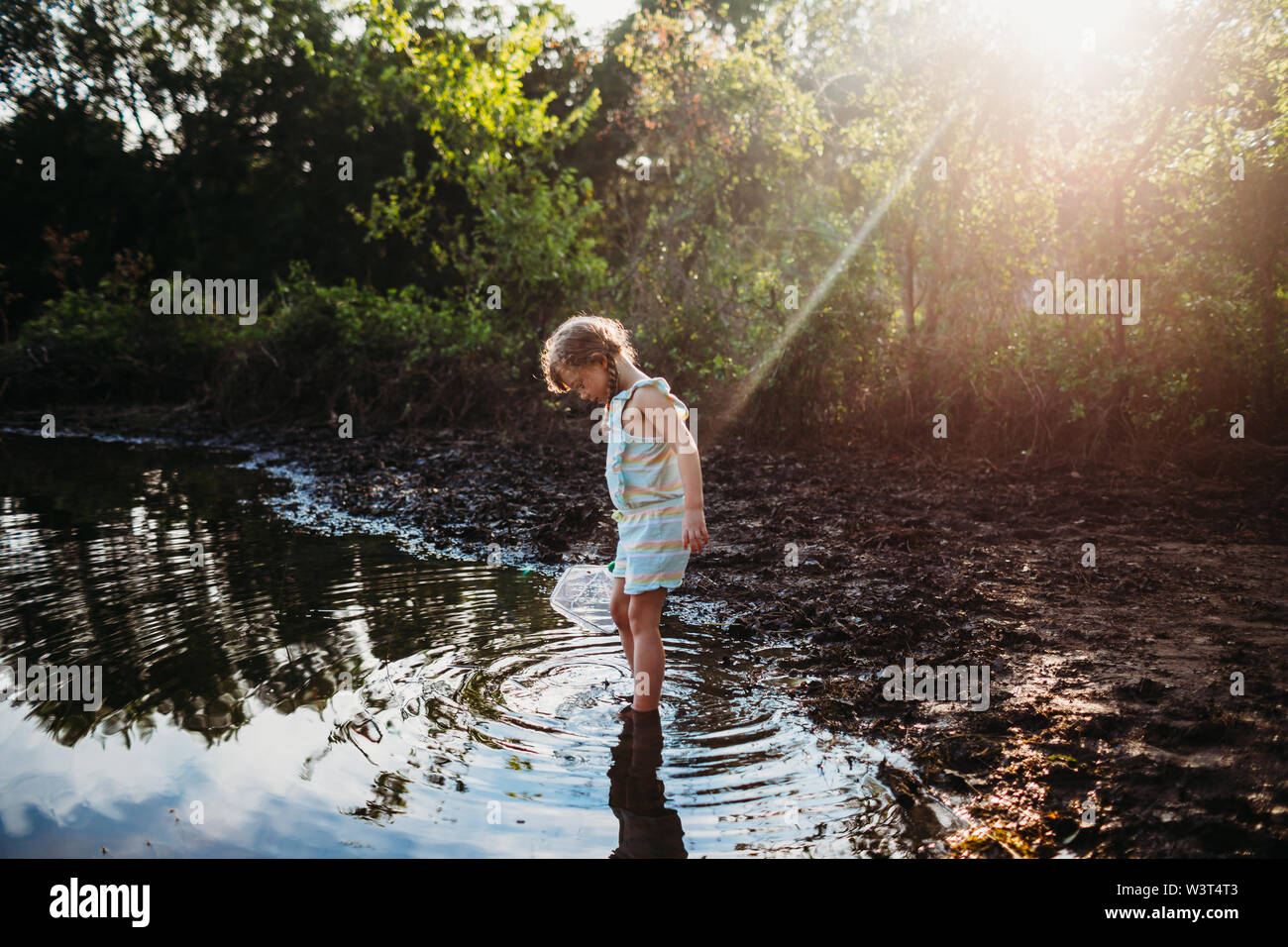 Jeune fille steping dans l'eau au lac tenant un filet de pêche Banque D'Images