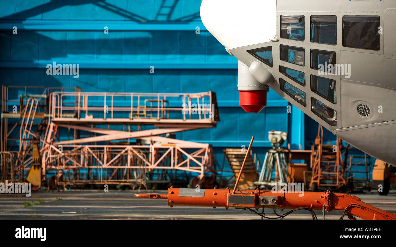 Le nez de l'appareil contre le hangar bleu. des échelles mobiles, des fenêtres d'observation Banque D'Images