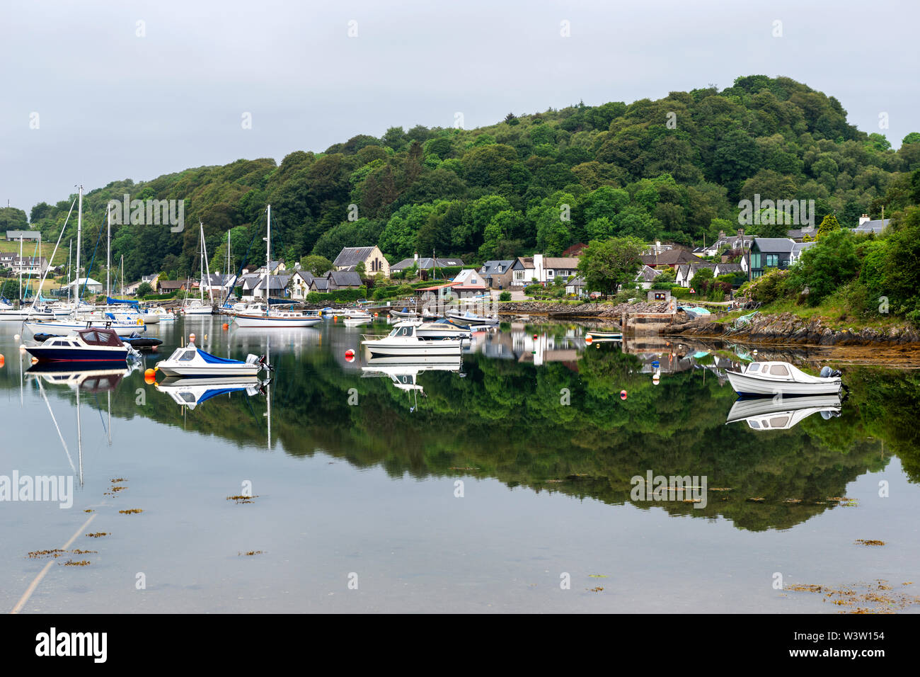 Tôt le matin les réflexions colorées de bateaux à l'ancre sur le Loch Sween au pittoresque village de pêcheurs de Tayvallich en Argyle et Bute, Ecosse, Royaume-Uni Banque D'Images