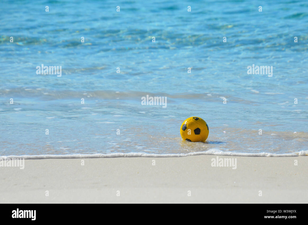 Ballon de soccer dans l'eau à la plage. Concept sport et style de vie en plein air actif sain jouant au football sur la plage. Banque D'Images