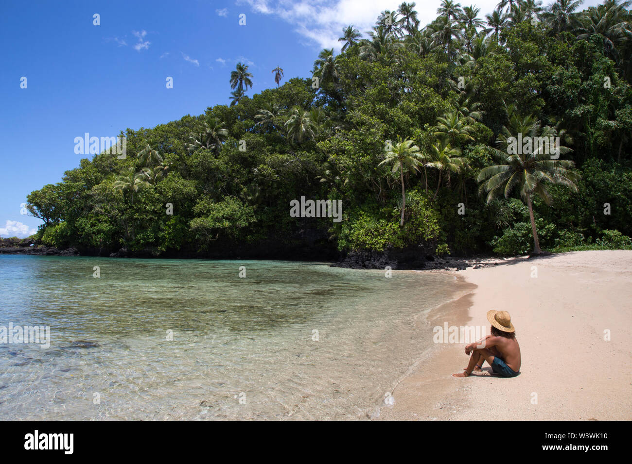Homme bronzé, assis sur la plage tropicale de sable, au cours de la journée d'été ensoleillée Banque D'Images