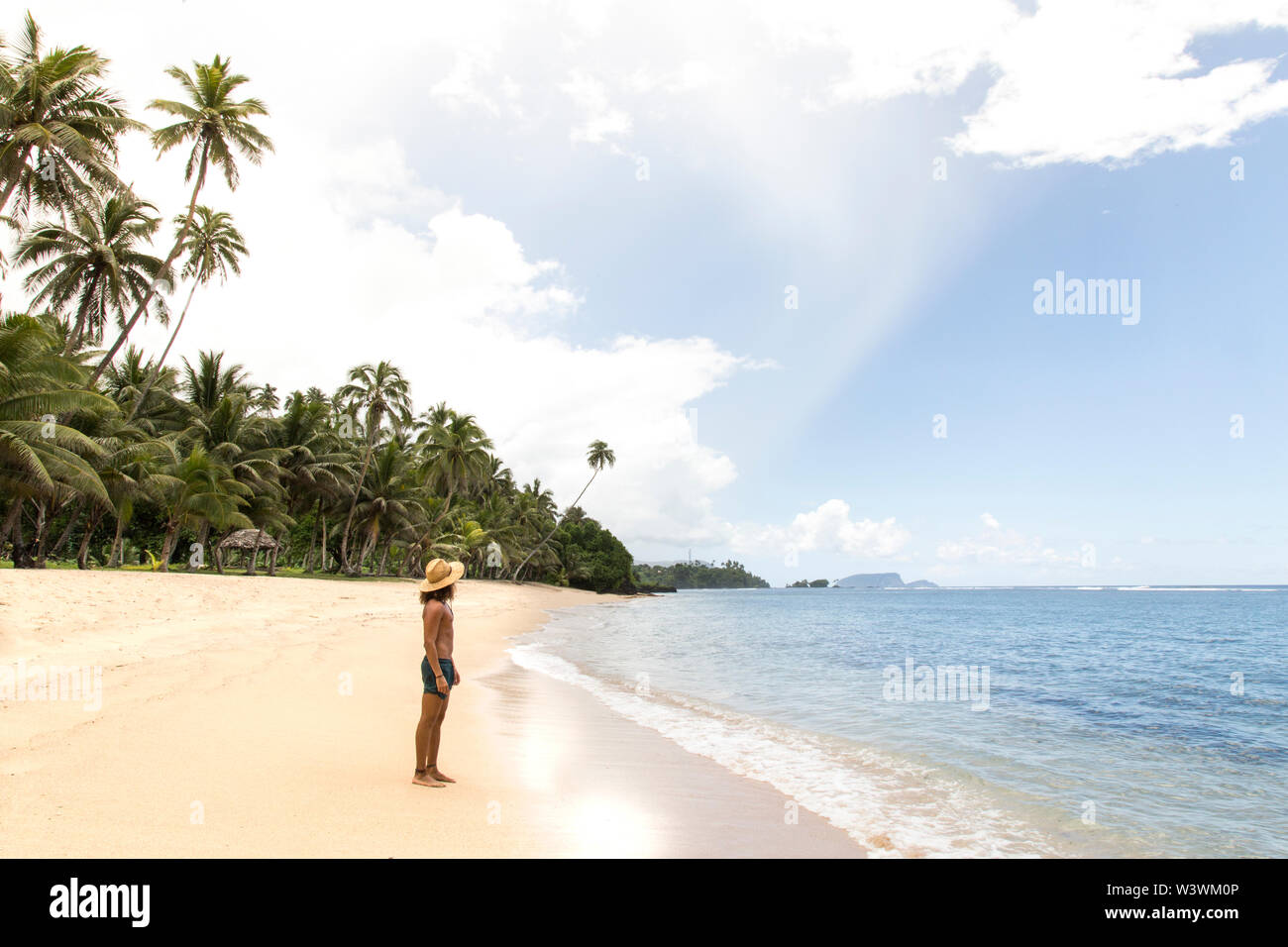 Un homme, vêtu d'bathingsuit vert, regardant la mer au cours de l'heure d'été Banque D'Images