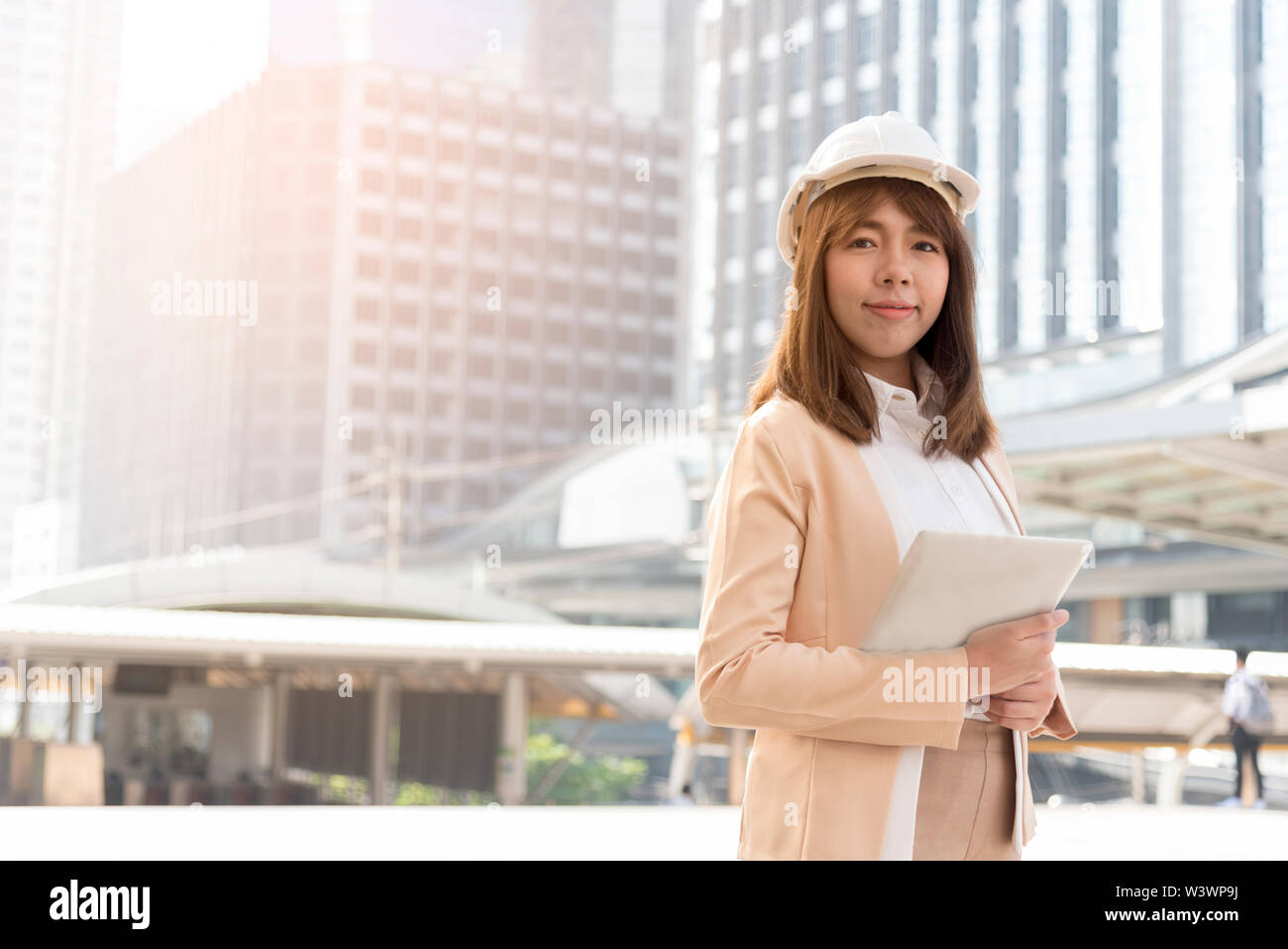 Bonheur Belle usure ingénieur sécurité, casque blanc debout devant grand bâtiment dans la ville. Banque D'Images