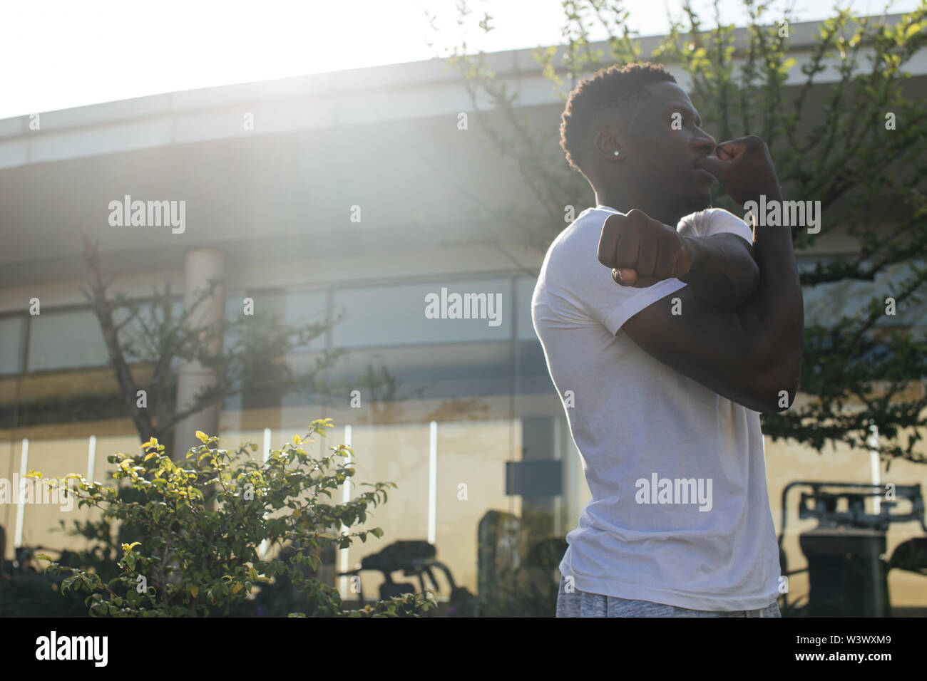 Portrait of African American man stretching armes dans la rue. Remise en forme de jeunes hommes guy faire réchauffer dans le matin Banque D'Images