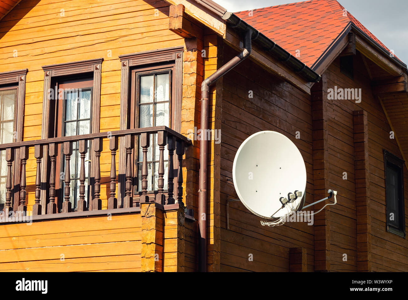 Parabole blanche satellite antenne plat pendu sur le mur de la villa moderne en bois maison de campagne. Récepteur de télévision sans fil Banque D'Images