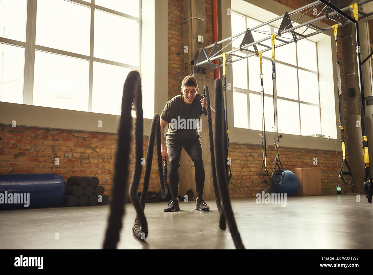 Bataille des cordes d'exercices. Jeune homme fort et faire des exercices CrossFit avec une corde à la salle de sport. Formation CrossFit. Sport concept Banque D'Images