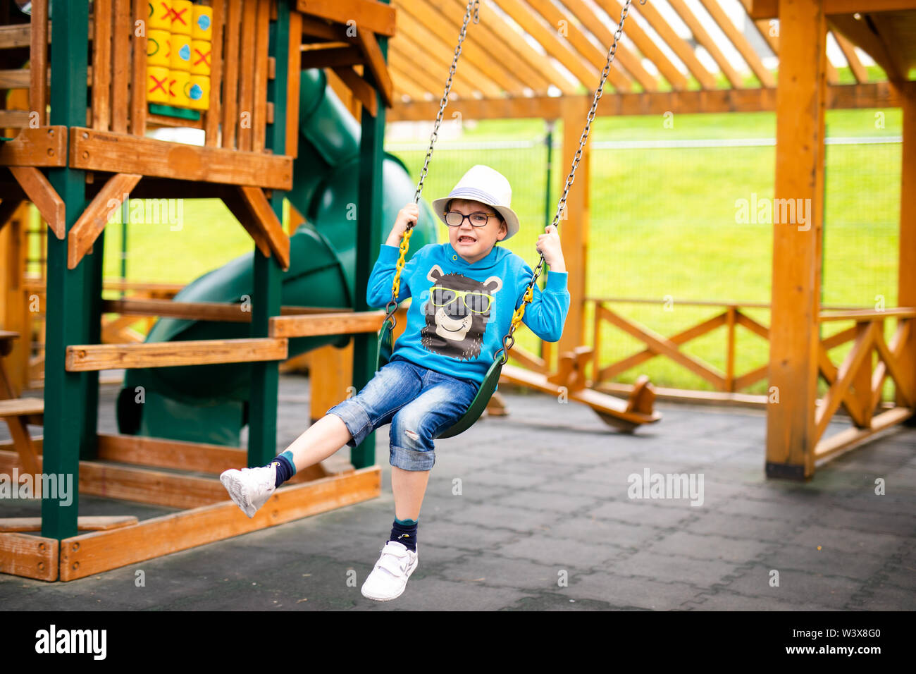 Enfant avec chapeau de paille et grands verres jouant sur une aire de jeux  extérieure. Kid active sur swing coloré. Activité d'été en bonne santé pour  les enfants. Petit garçon swi Photo