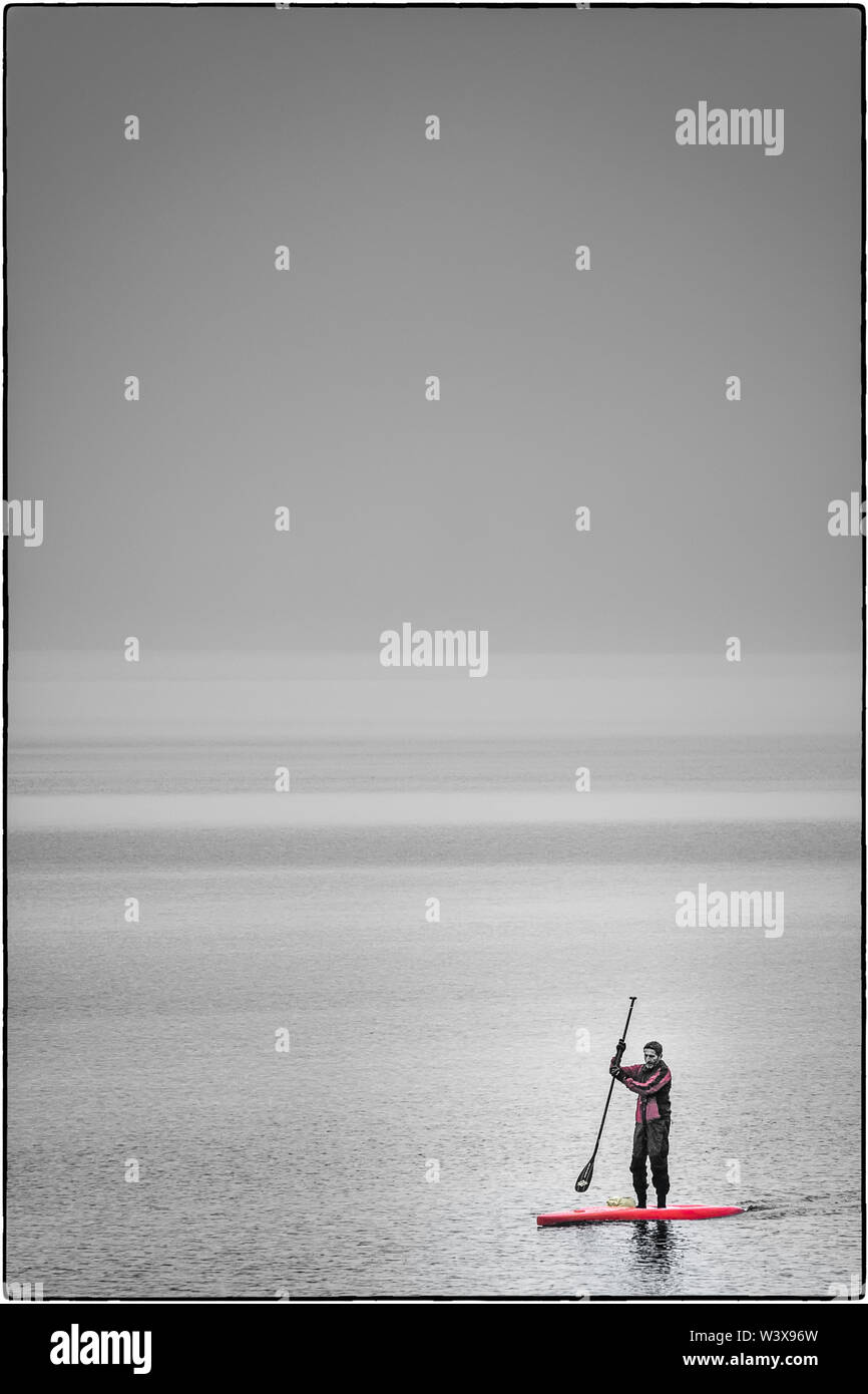 Poussant autour dans le brouillard photo gris avec undefined frontières entre brouillard et lac avec un Stand Up Paddler couleur en avant-plan Banque D'Images