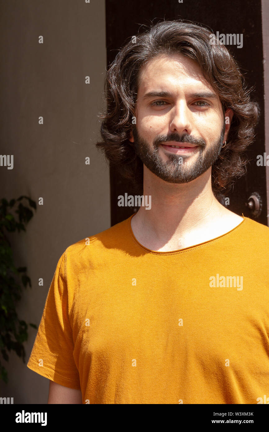 Portraits d'un jeune homme dans la rue, à la caméra à tout sourire avec un t-shirt orange Banque D'Images