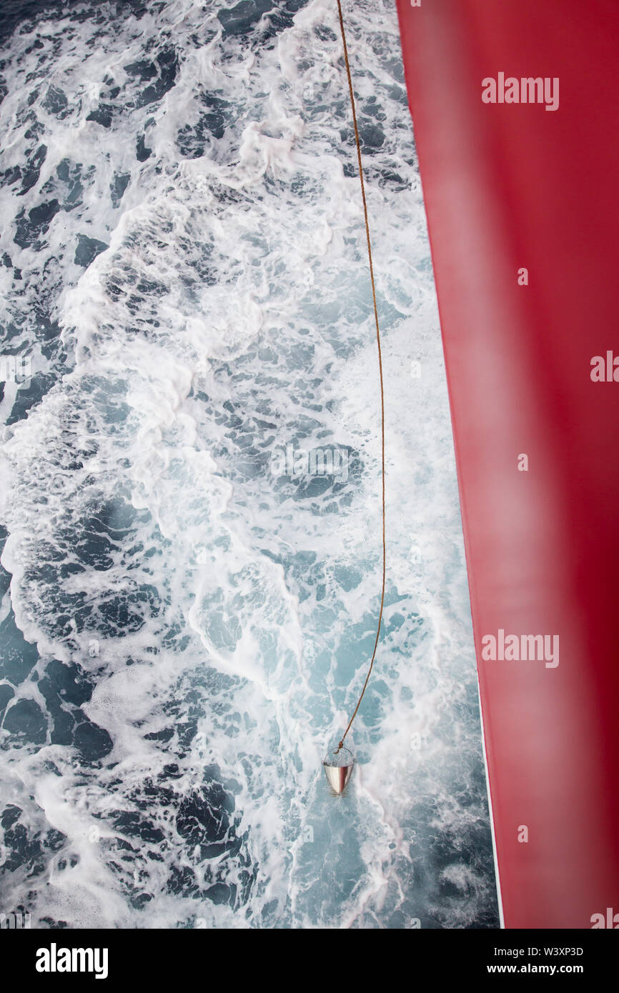 Un chercheur tombe un seau par-dessus bord afin de prélever des échantillons d'eau sur un navire de recherche effectuer une croisière océanographique scientifique dans l'Atlantique Sud Banque D'Images