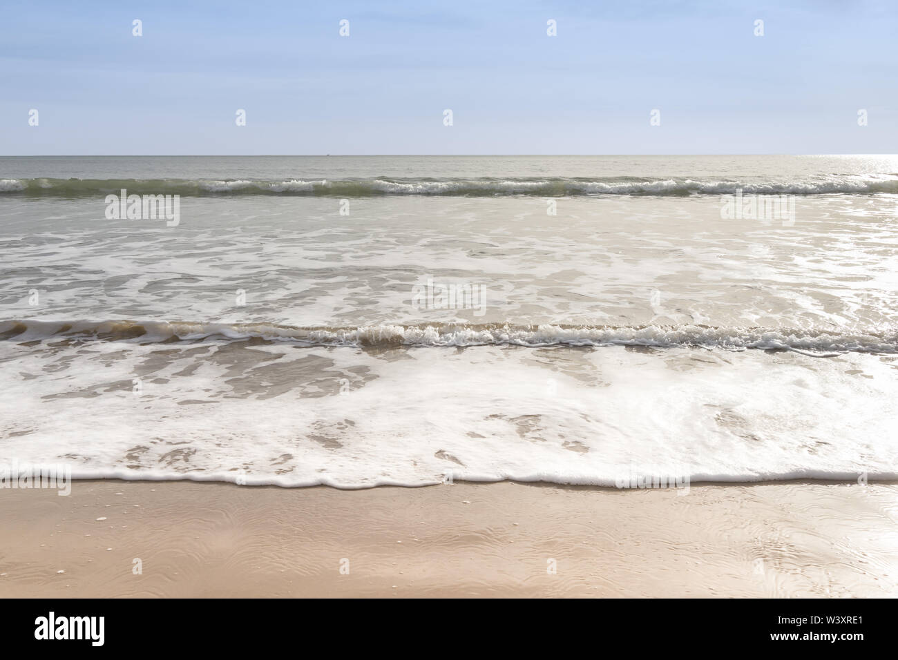 Clapotis des vagues doucement sur une plage de sable fin avec ciel bleu Banque D'Images